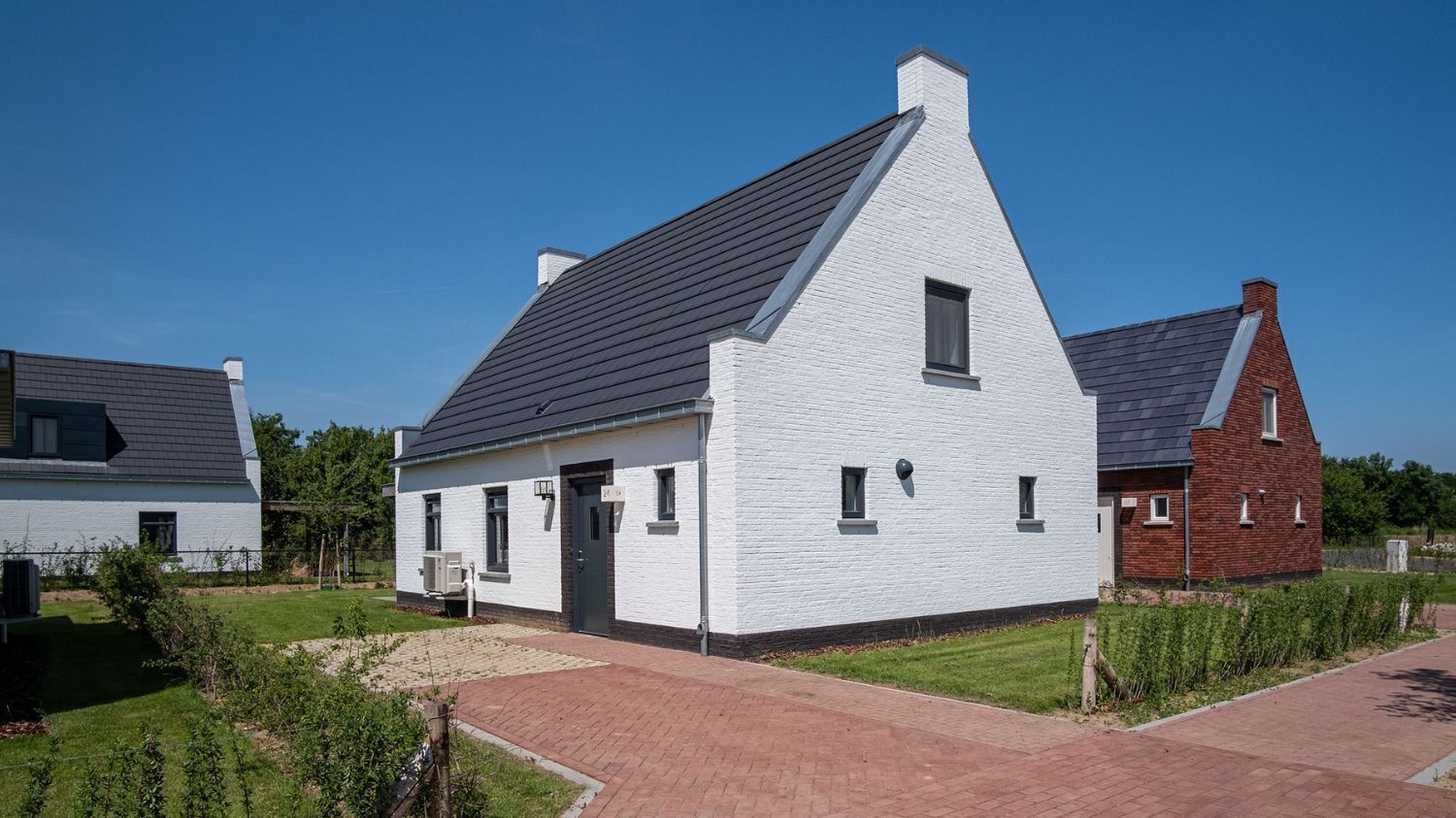Une maison blanche à deux étages, dotée d’un toit à pignon abrupt, d’une cheminée en briques et d’un petit porche à l’avant.