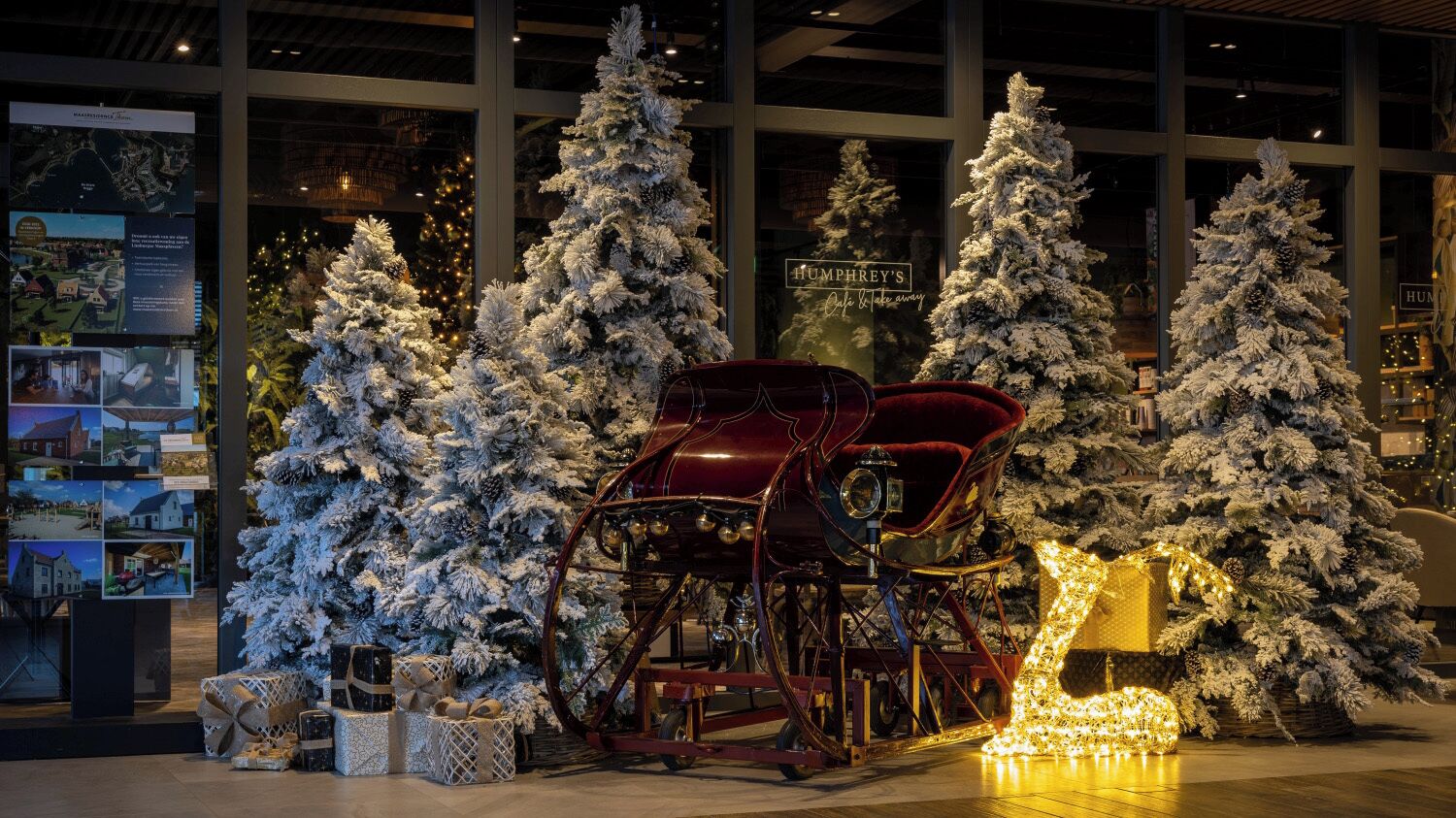 A Christmas display with frosted trees and a sleigh in a hotel lobby.