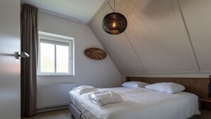Un dormitorio con cama, ventana, lámpara de pared y ventilador de techo.