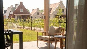 Un balcon avec une chaise et une table, une vue sur des maisons et une clôture.