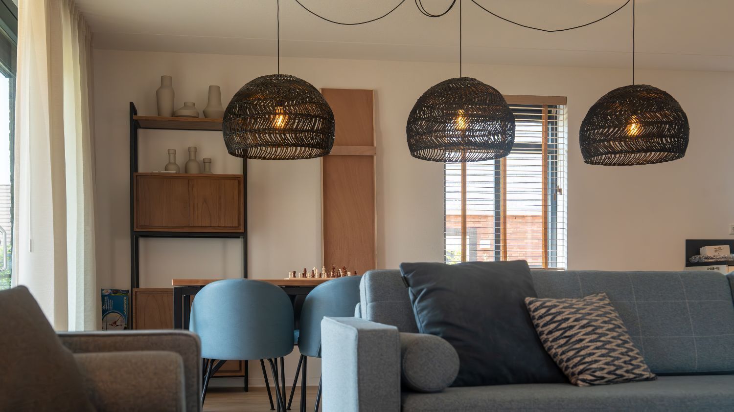 A modern living room with a sofa, chairs, a chessboard, and pendant lights.