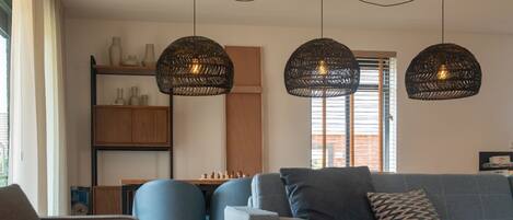 A modern living room with a sofa, chairs, a chessboard, and pendant lights.