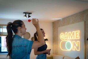 A room with a neon sign that reads "GAME ON" on the wall.