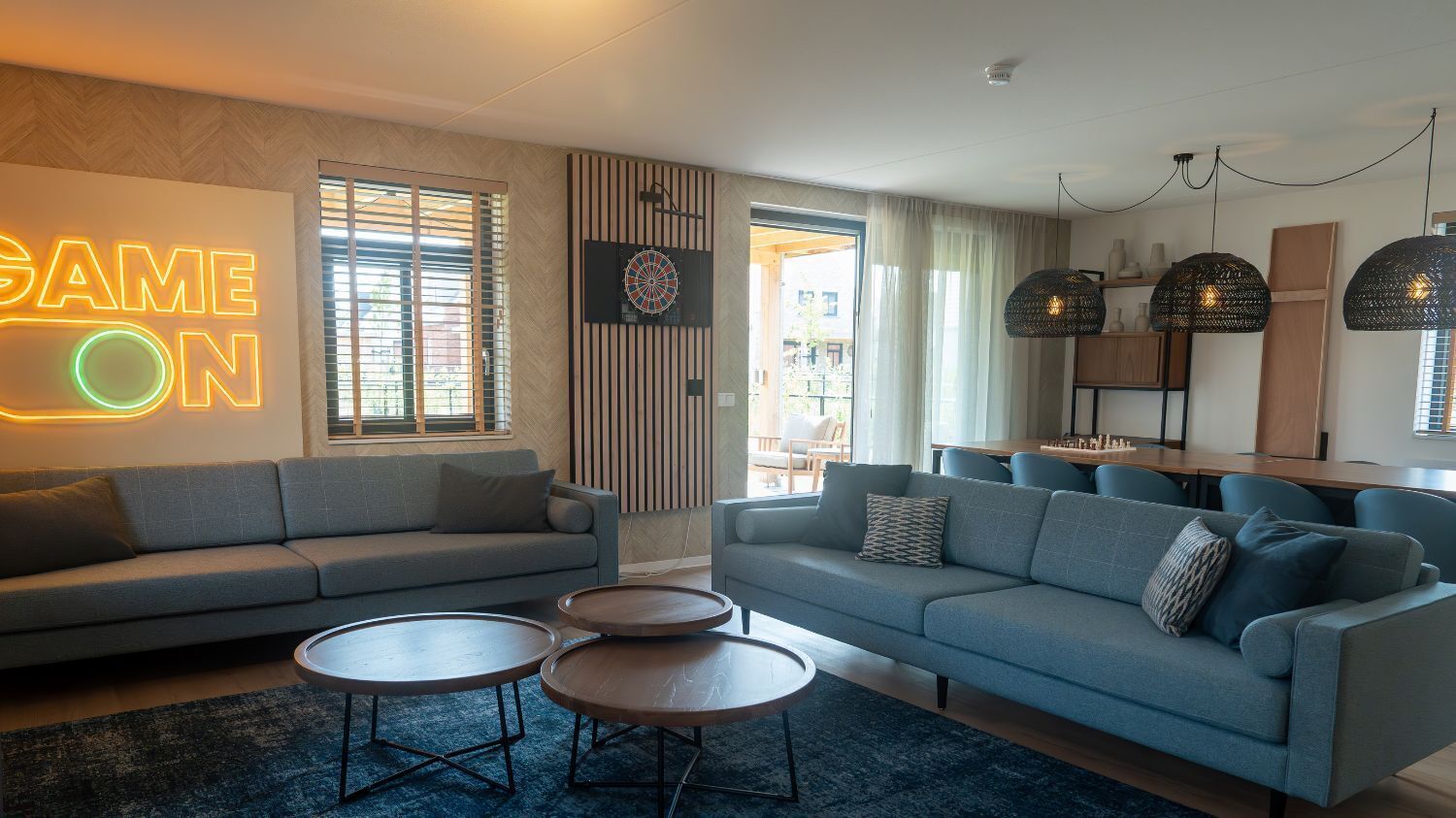 A modern living room with a sofa, coffee table, and a dartboard on the wall.