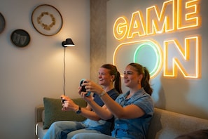 Two people playing video games on a couch with a neon sign that reads "GAME ON" in the background. - Premium Game 12p - Six Bedroom Villa, Sleeps 12 (Thorn)