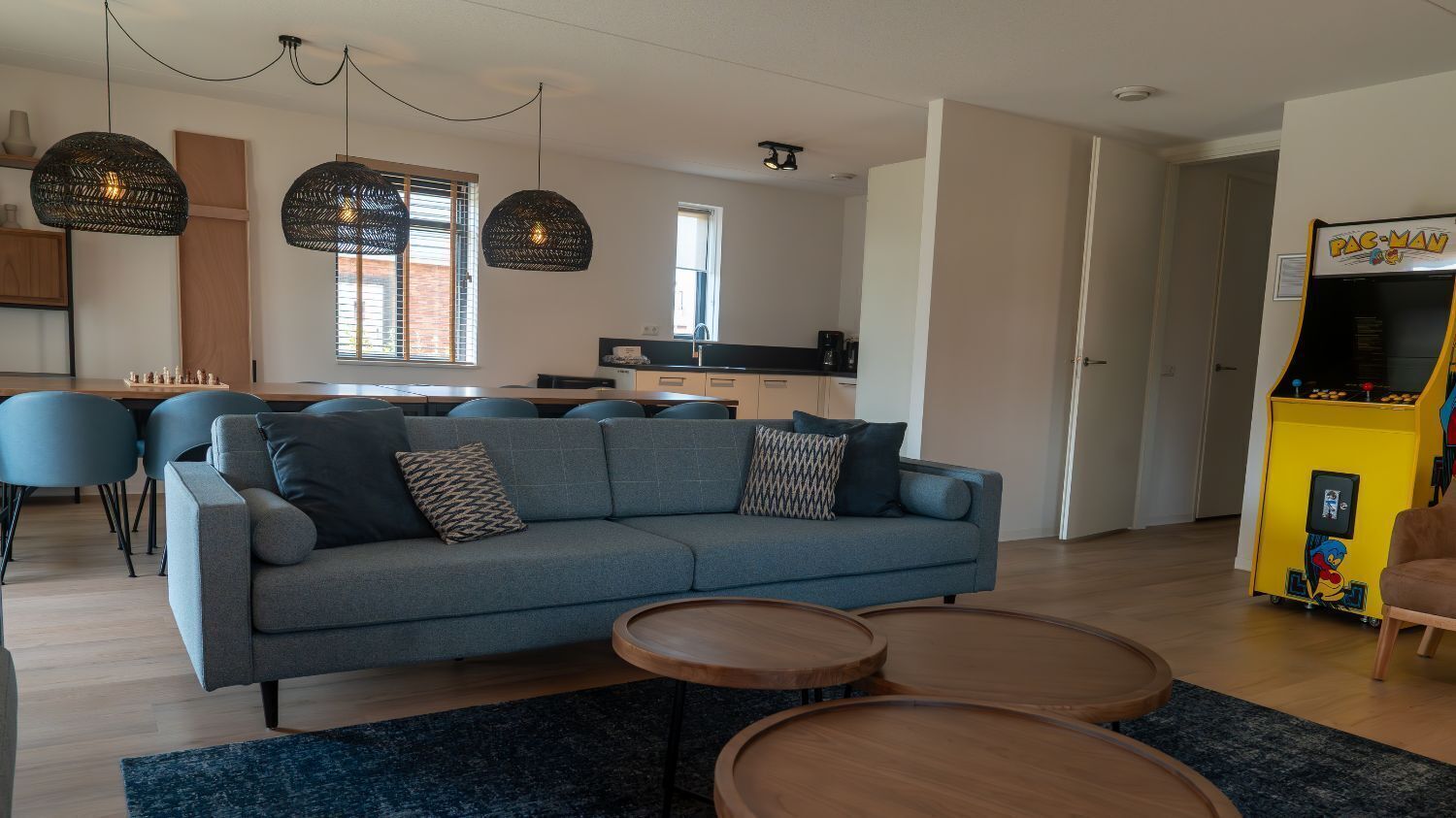Een moderne woonkamer met een bank, salontafel en een Pac-Man arcadekast.