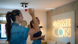 Una habitación con un letrero de neón en la pared que dice 'GAME ON'.