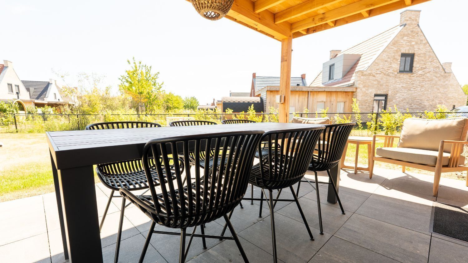 An outdoor patio with a table and chairs, a hanging light fixture, and a stone building in the background.