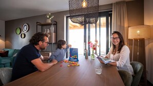 Zona pranzo con un tavolo in legno, un gioco da tavolo e un vaso con fiori.