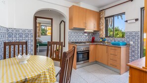 A kitchen with wooden cabinets, a gas stove, and a blue sink. - Country House 'Ivone' with Sea View, Private Pool and Wi-Fi (Portimão)