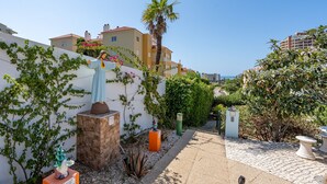 A courtyard with a statue, a palm tree, and a stone wall. - Country House 'Ivone' with Sea View, Private Pool and Wi-Fi (Portimão)