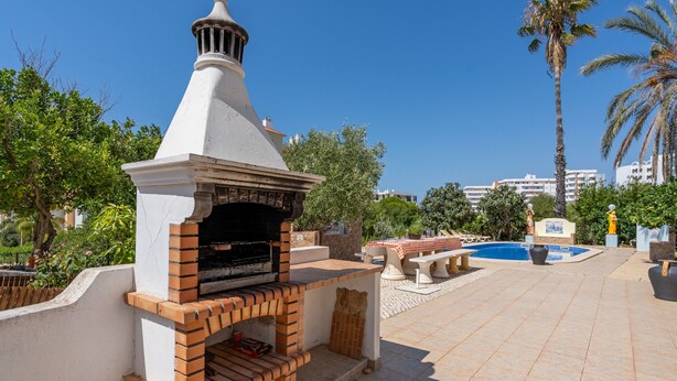 An outdoor barbecue area with a brick oven, a pool, and palm trees. - Country House 'Ivone' with Sea View, Private Pool and Wi-Fi (Portimão)