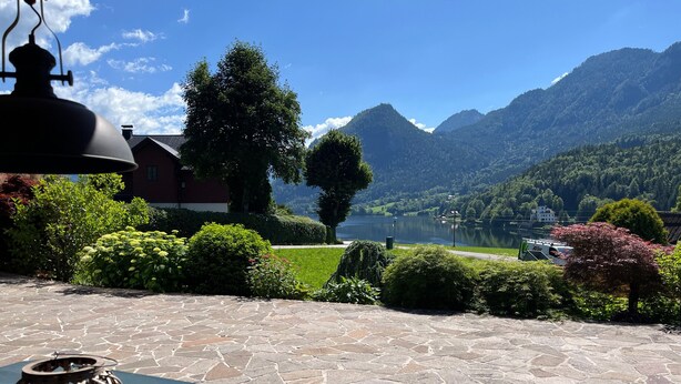 Eine Steinterrasse mit Tisch und Laterne mit Blick auf einen See und Berge.