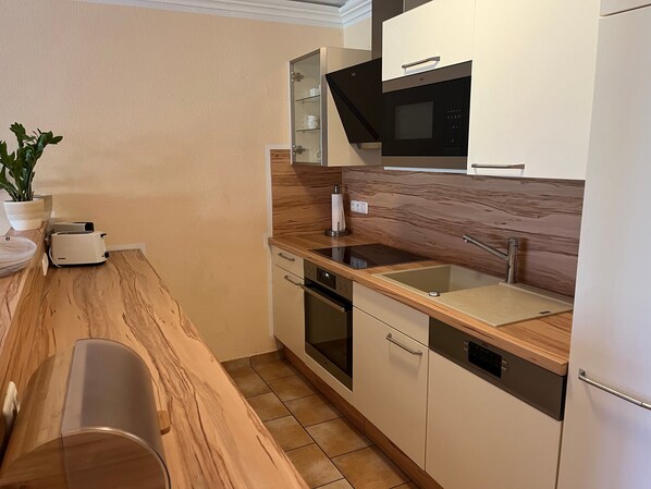 Een moderne keuken met een houten aanrecht, een ingebouwde magnetron en een vaatwasser.