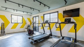 Une salle de sport équipée de tapis de course, d’un vélo d’appartement et d’un banc de musculation.