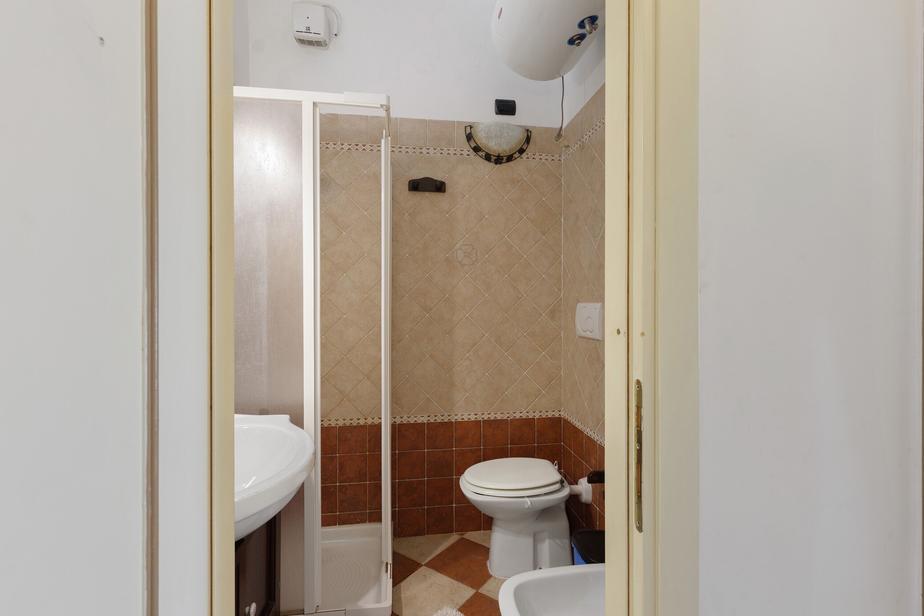 Un baño con inodoro, lavamanos y zona de ducha.