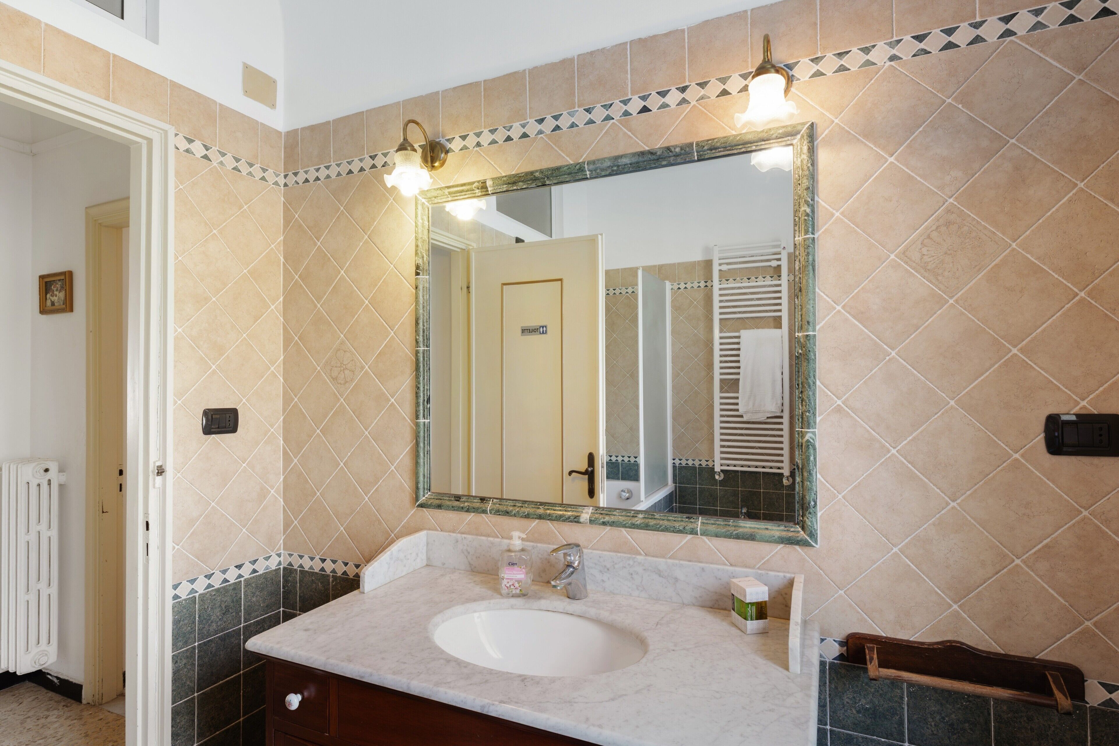 A bathroom with a sink, mirror, and towel rack.