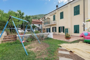 A residential building with a balcony, a swing set, and a garden area. - Room 'Fiordaliso' with Mountain View, Shared Terrace and Wi-Fi (Imperia)