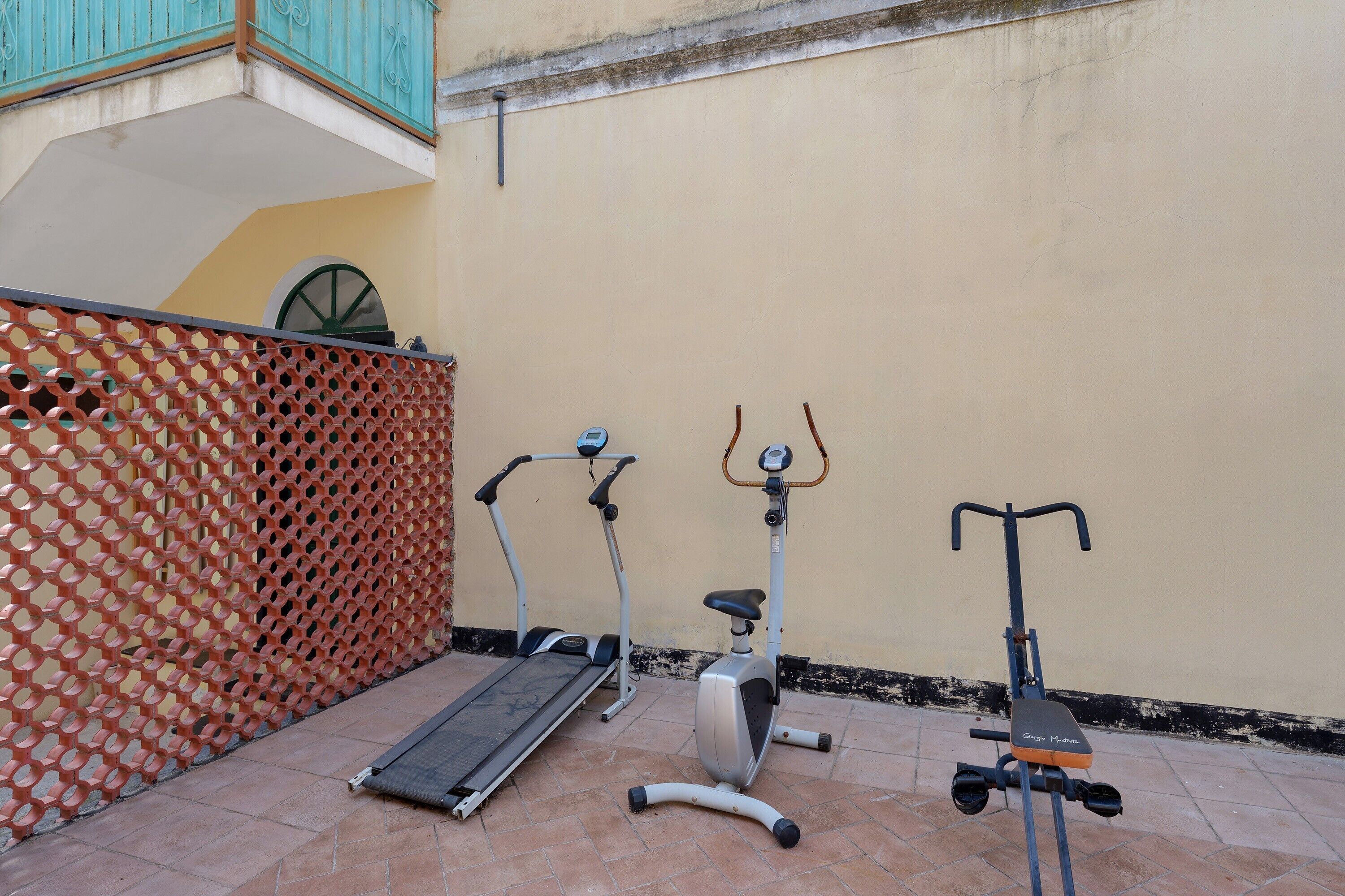 A patio with exercise equipment including a treadmill, stationary bike, and scooter.
