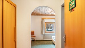 A hallway leading to a room with a window, a radiator, and a door with a sign. - Room '5' with Mountain View, Shared Terrace and Wi-Fi (Hopfgarten in Tirol)