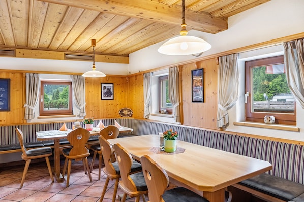 A wooden interior with a dining table, chairs, and a bench.