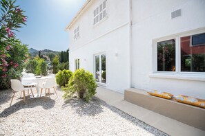A white building with a patio area, outdoor seating, and a small garden. - Charming house - L'Abricotier (Calvi)