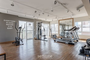 A gym with exercise equipment, large windows, and a motivational quote on the wall. - BVA - Complete Condominium With Pool in Sao Paulo (São Paulo)
