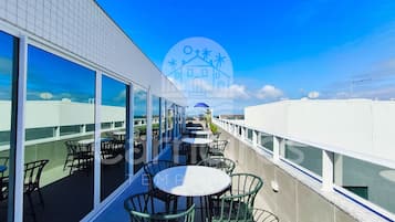 Terraço no telhado com área de estar externa, janelas amplas e vista desobstruída do céu.
