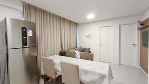 A compact hotel room with a dining area, a refrigerator, a bed, and a door. - Mila Rooftop - Praia de Tamandaré (Tamandaré)