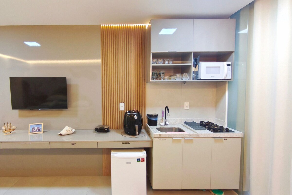 A modern kitchen with a flat-screen TV, a coffee maker, and a microwave.