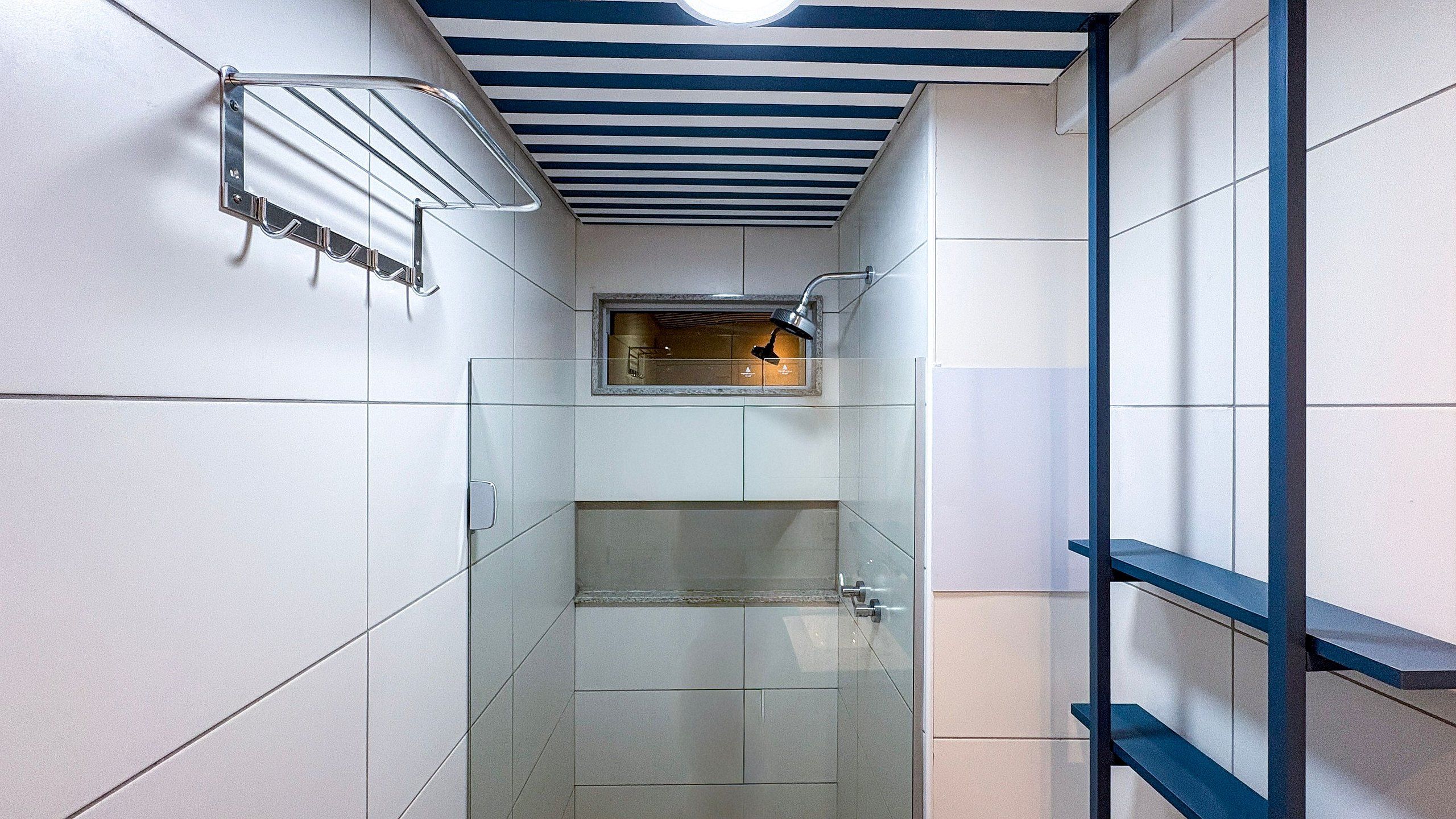 A narrow bathroom with a shower, a towel rack, and a ceiling light fixture.