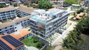 A multi-story building with a rooftop pool, solar panels, and a parking area. - Mila Rooftop - Praia de Tamandaré (Tamandaré)