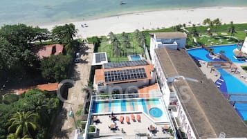 A resort with a swimming pool, beach view, and solar panels.