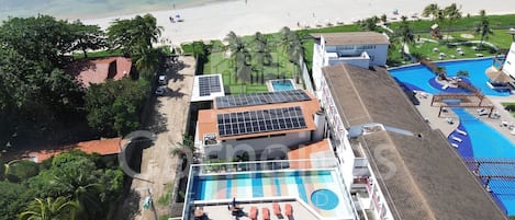 A resort with a swimming pool, beach view, and solar panels.