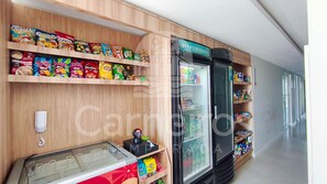 A snack display with various brands, a refrigerated section, and a freezer. - Mila Rooftop - Praia de Tamandaré (Tamandaré)
