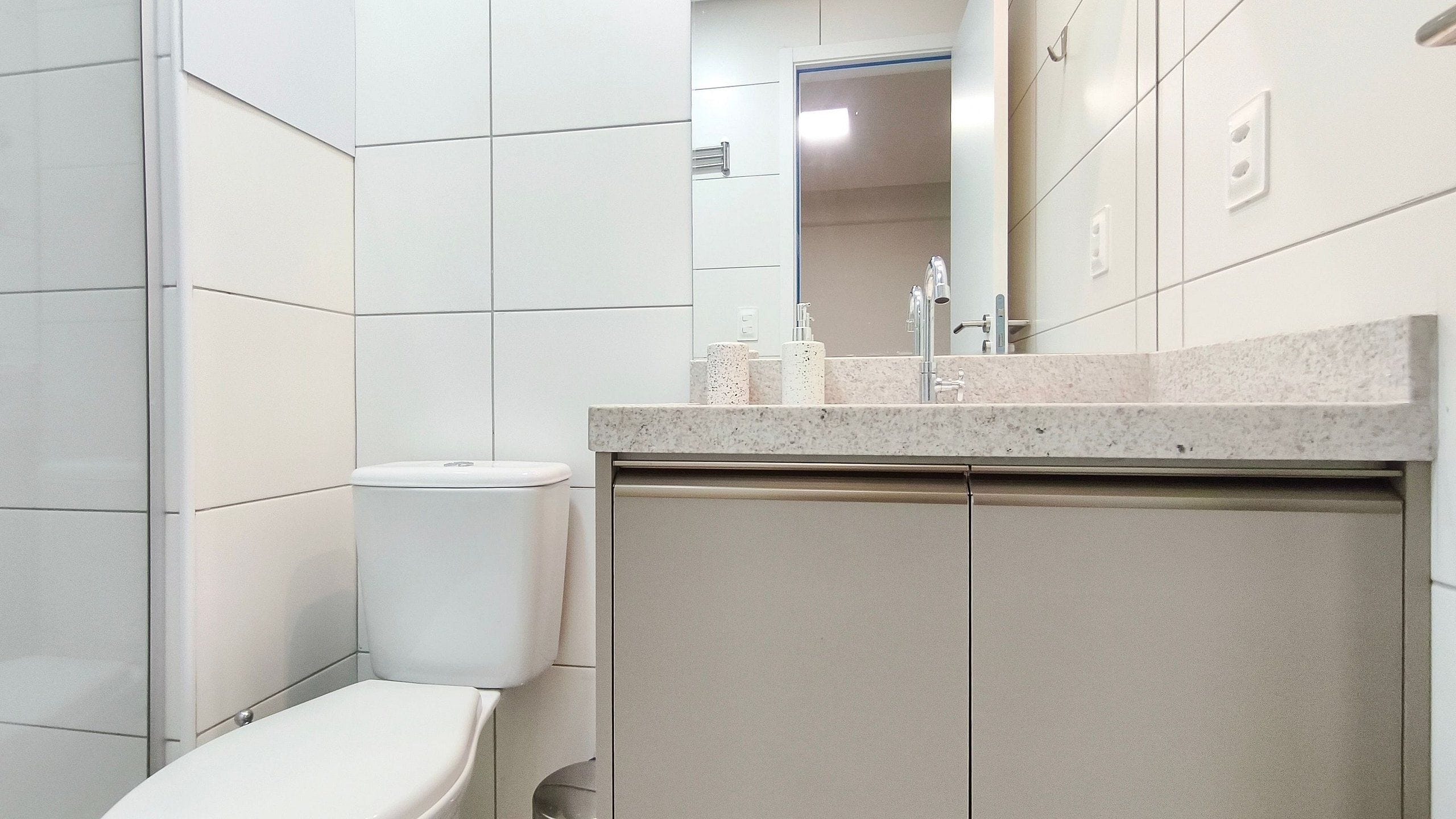 Ein Badezimmer mit Toilette, Waschbecken mit Spiegel und einem Schrank.