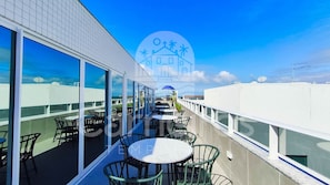 A rooftop terrace with outdoor seating, large windows, and a clear view of the sky. - Mila Rooftop - Praia de Tamandaré (Tamandaré)