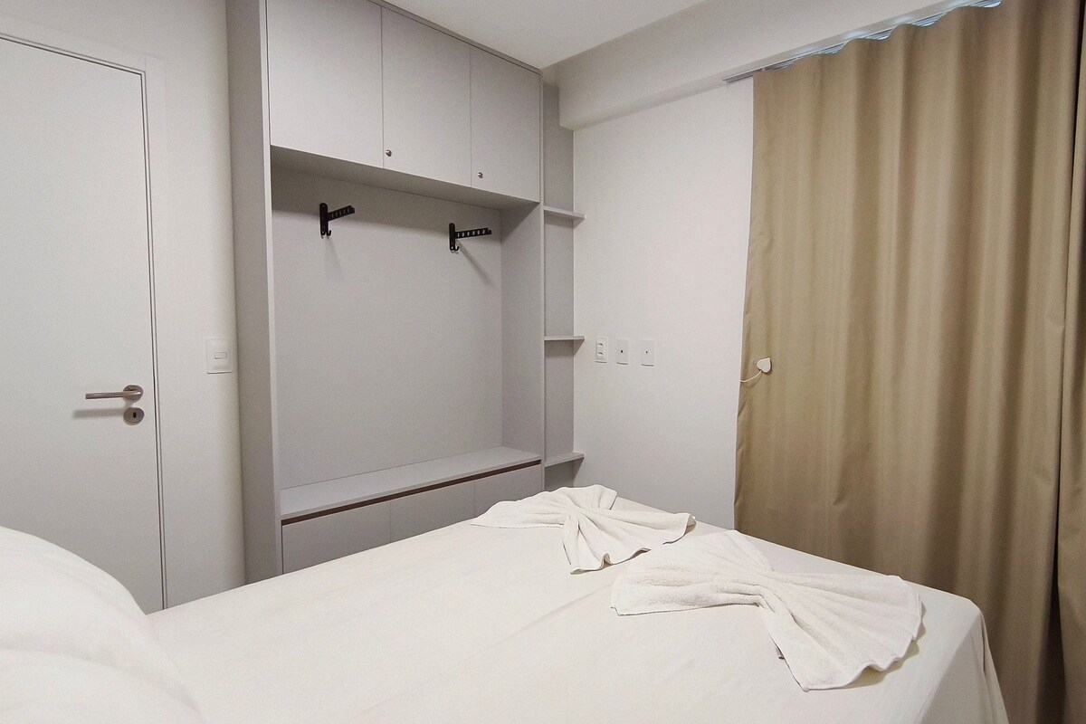 A hotel room with a bed, a wardrobe, and a curtain.
