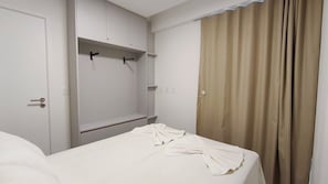 Una habitación de hotel con una cama, un armario y una cortina.