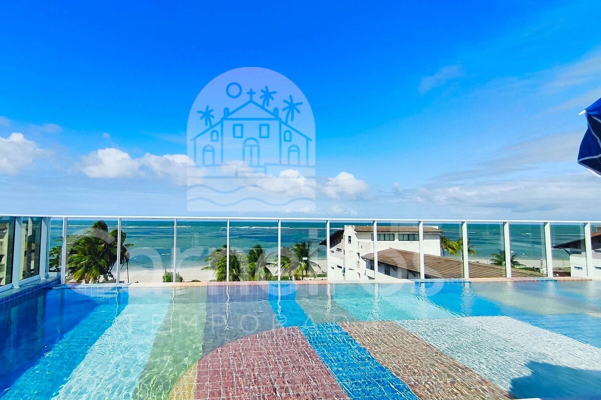 Una piscina con agua cristalina, vista a la playa y un entorno tropical.