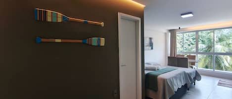 A hotel room with a bed, a bathroom, and a view of palm trees.