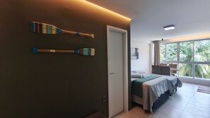 A hotel room with a bed, a bathroom, and a view of palm trees.