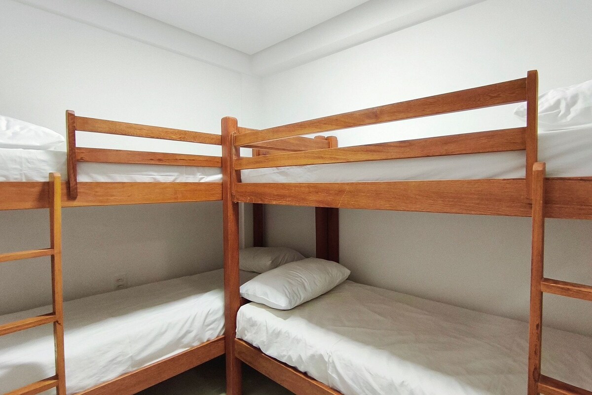 Dormitorio con literas de madera y ropa de cama blanca.