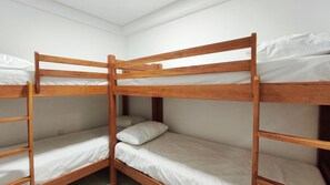 Ein Schlafzimmer mit Etagenbetten, Holzrahmen und weißer Bettwäsche.