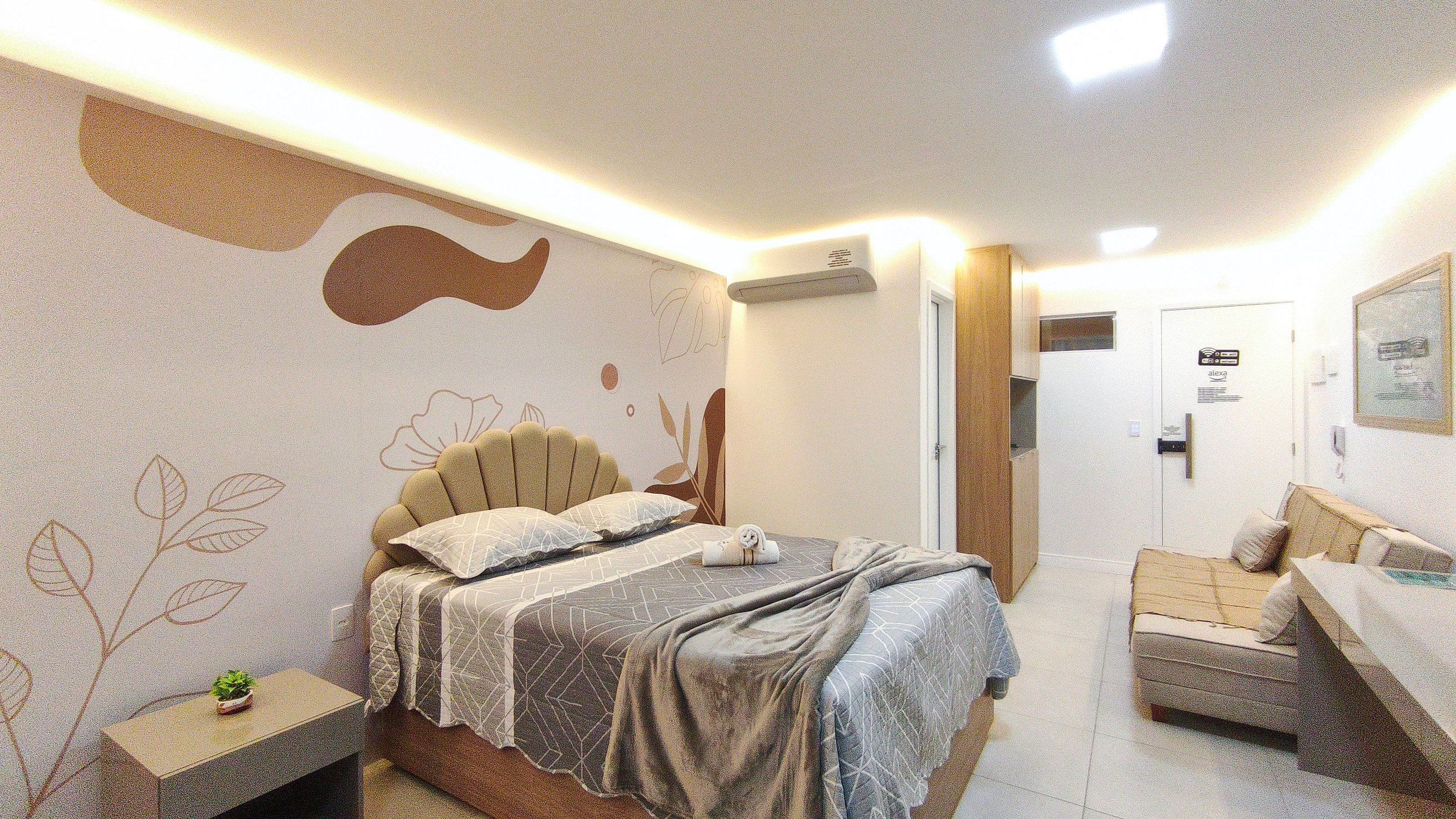A hotel room with a bed, bedside table, and a sofa.
