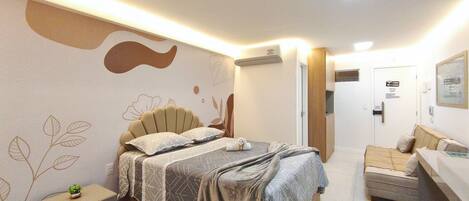 A hotel room with a bed, bedside table, and a sofa.