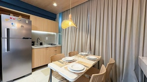 A compact kitchen with a refrigerator, stove, and dining table set for four. - Mila Rooftop - Praia de Tamandaré (Tamandaré)