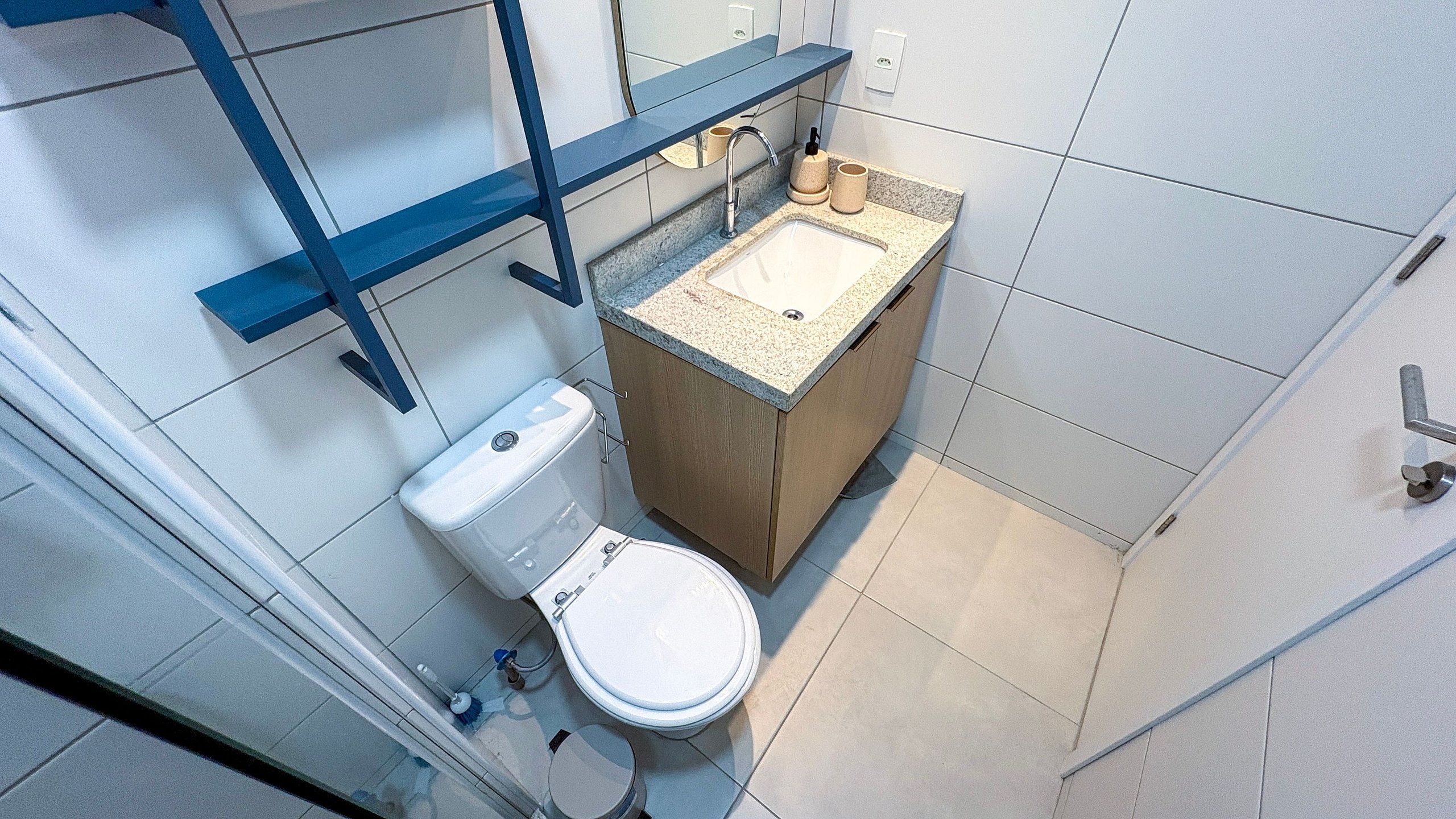 Casa de banho compacta com sanita, lavatório e um pequeno armário.