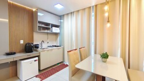 A compact kitchen with a microwave, sink, and small refrigerator. There is a dining table with chairs and a potted plant. - Mila Rooftop - Praia de Tamandaré (Tamandaré)