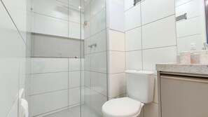 A modern bathroom with a glass shower enclosure, a toilet, and a marble countertop.